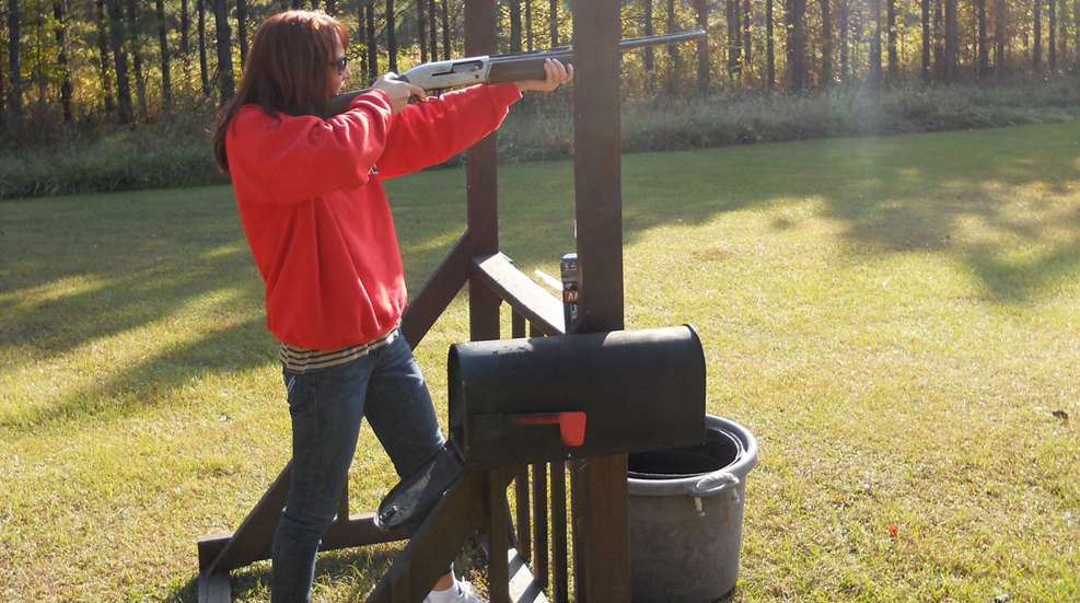 Woman Pointing Shotgun At Clays Station