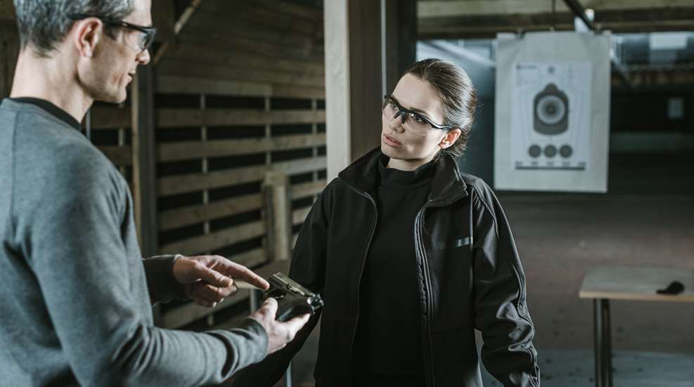 Male Firearm Instructor With Women On Range
