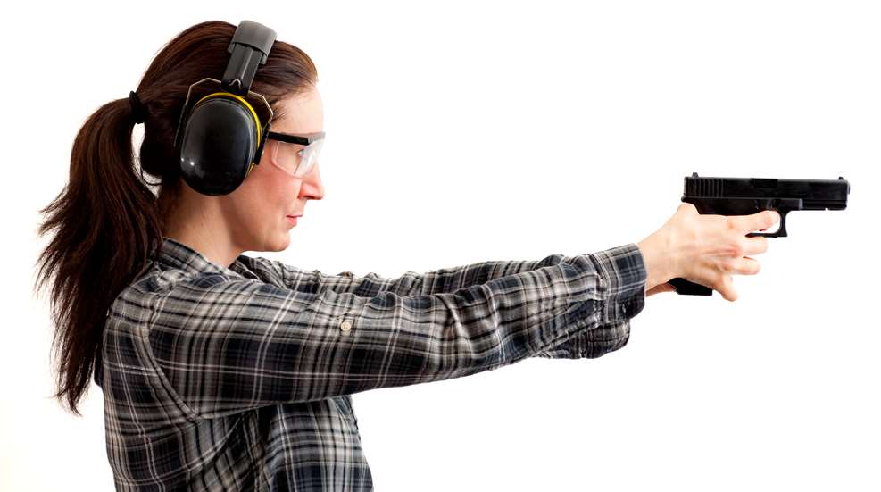 Woman with gun at range wearing ear protection
