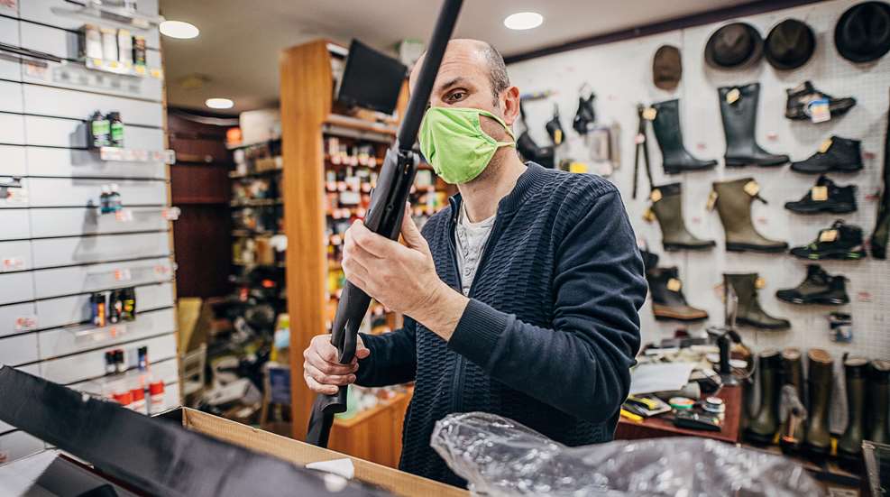 Man Looking At Rifle In Gun Store (1)