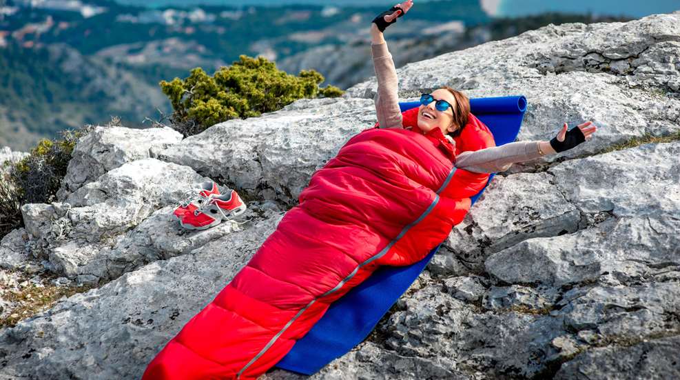 Woman In Sleeping Bag On Rocks