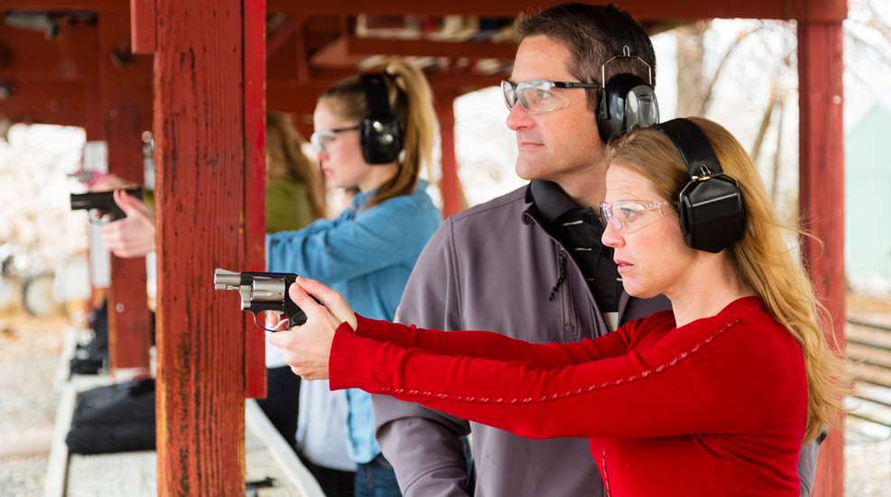 Man Helping Woman At Gun Range