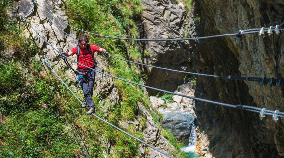 Man Crossing Rope Bridge