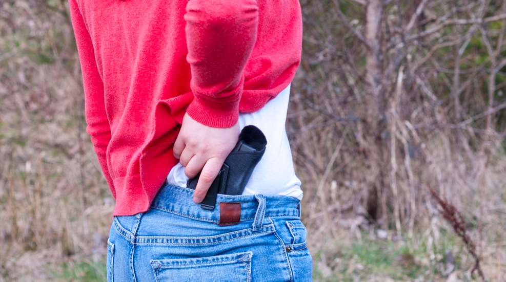 Woman Reaching For Concealed Firearm In Holster