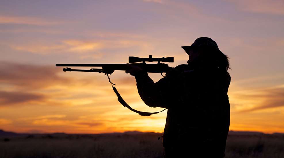 Woman Holding Rifle At Sunset