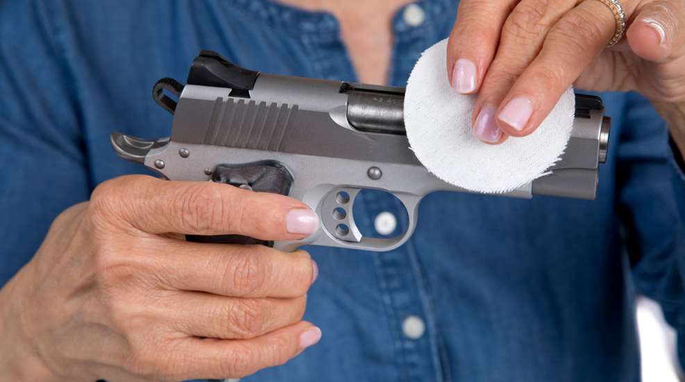 Woman Hand Wiping Down Firearm With Cleaning Patch