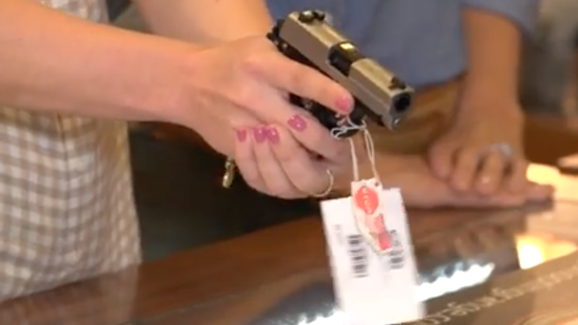 Woman Trying Gun At Counter